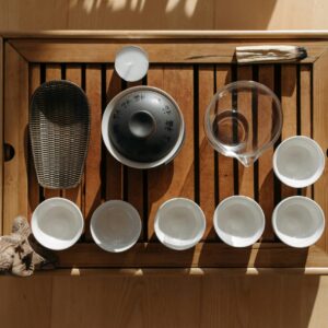A top-down view of a wooden tray set up for a traditional tea ceremony, featuring teacups and accessories.