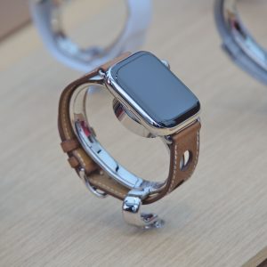Close-up of a sleek smartwatch with a leather strap displayed on a wooden surface.