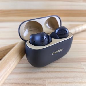 Modern Realme wireless earbuds in a sleek case on a wooden background, combining style and tech.