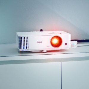 Stylish white projector on a cabinet with glowing lens, perfect for presentations and media rooms.